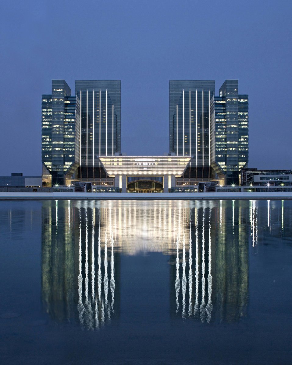 ADGM headquarters at dusk reflected in water